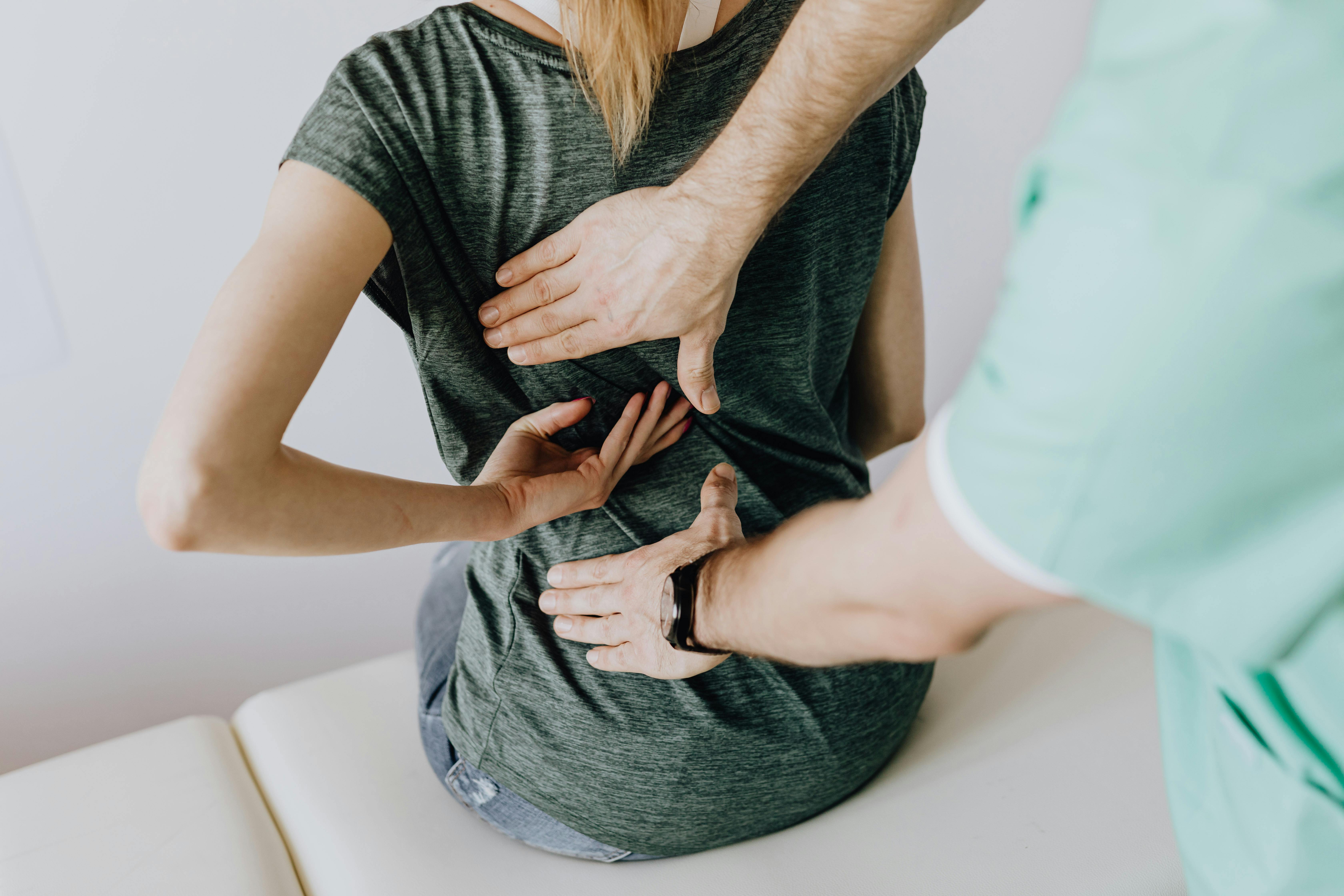 Chiropractor performing a low back assessment on a seated patient