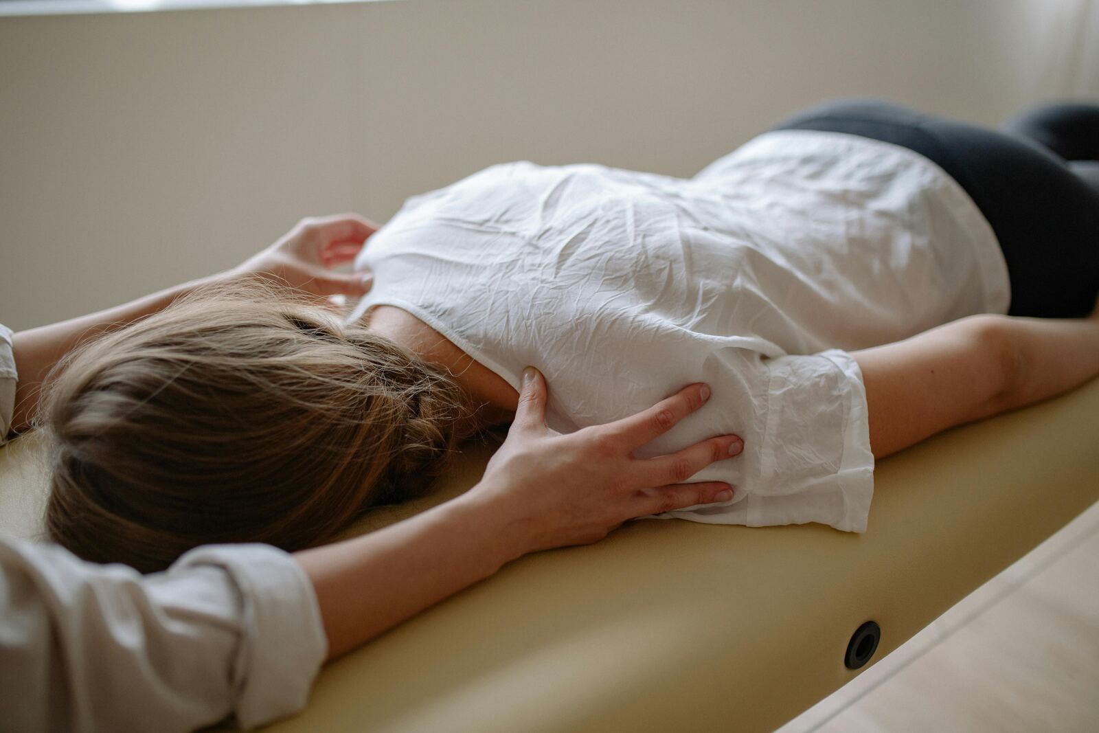 Patient lying face down on a chiropractic table receiving a shoulder adjustment